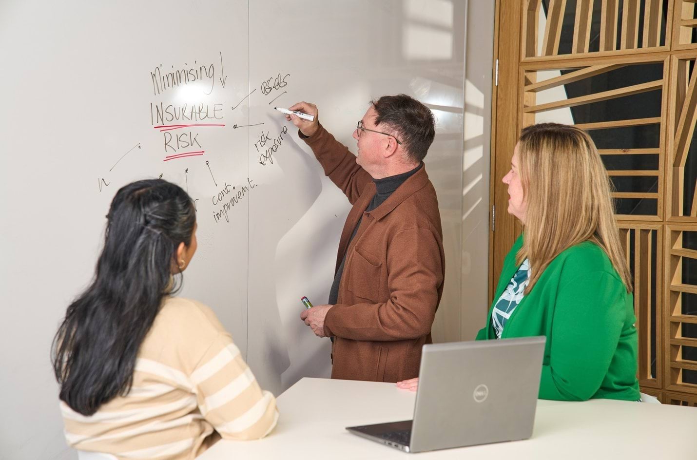Educator writing on a whiteboard, teaching minimising Insurable Risk